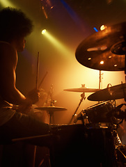 Image showing Stage, drummer and man in performance at concert playing jazz, beat and talent for music. Drums, musician and person in theater spotlight with instrument for percussion, rhythm and show at night