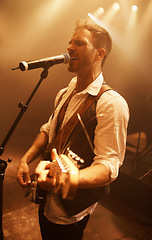 Image showing Singer, music and guitar with man on stage for concert, performance and rock show. Event, spotlight and energy with male musician playing instrument at festival club for rave, disco and celebration