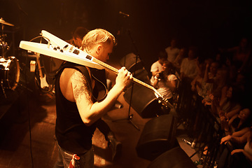 Image showing Guitar, musician and stage concert at night with man in performance of rock or metal music. Festival, event and rocker playing for crowd with talent or dance in theater and club with light and energy