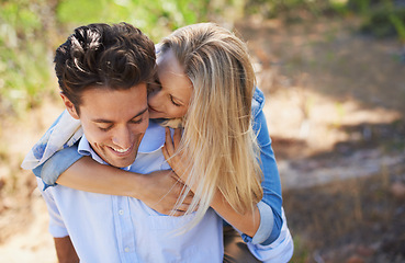 Image showing Happy couple, kiss and cheek in piggyback for love, bonding or support for outdoor affection in nature. Face of young woman and man smile for embrace, hug or romantic back ride in forest together