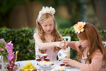 Image showing Playing, tea party and girl children in garden for pretend with cake, flowers or kid fun. Princess, cookies and fantasy with friends, teapot and backyard with celebration, imagination and drink.