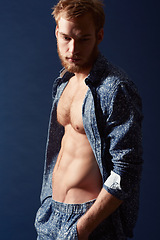 Image showing Fashion, thinking or ginger model with body in studio on a blue background wearing an open unbuttoned shirt. Man, abs or handsome male person posing on color wall for masculine style with six pack