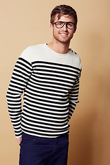 Image showing Fashion, glasses and portrait of man in studio in trendy, stylish and casual clothes on beige background. Happy, attractive and person with stripe style for positive attitude, pride and confidence