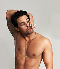Image showing Shirtless, cigarette and man smoking in a studio for grungy, cool and attractive personality. Confidence, chest and young male model from Canada with tobacco for smoke isolated by gray background.
