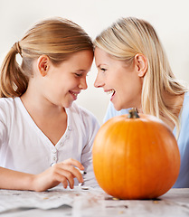 Image showing Mother, daughter or happy with pumpkin for halloween, celebration or decoration in kitchen of apartment home. Family, face or smile and vegetable for preparation, holiday or creative event in house