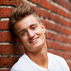 Image showing Smile, portrait and young man on a brick wall in the city to relax and explore in Australia with pride. Happy, face and male person or student on an urban background with confidence while relaxing