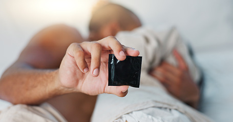 Image showing Hand, condom and people in bed for sex, protection and contraception with lust and desire on Valentines day. Intimacy, health and safety for couple bonding in bedroom with rubber and sexual moment