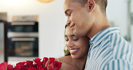 Image showing Happy couple, red roses and kiss for surprise, anniversary or valentines day in kitchen at home. Face of young man and woman smile with flowers for romantic gift, love or care in celebration at house