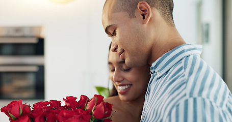 Image showing Happy couple, red roses and kiss for surprise, anniversary or valentines day in kitchen at home. Face of young man and woman smile with flowers for romantic gift, love or care in celebration at house