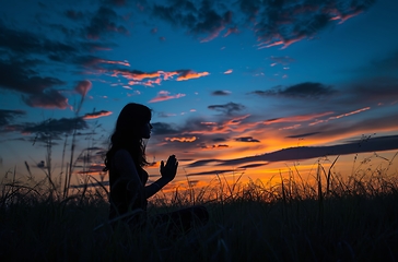 Image showing Woman Kneeling in Field at Sunset - Serene and Contemplative Moment Captured in Nature