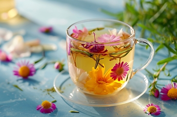 Image showing Glass Cup Filled With Water and Flowers, A Serene Floral Arrangement