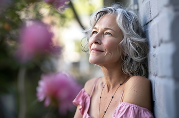 Image showing Woman Leaning Against Wall With Background of Flowers