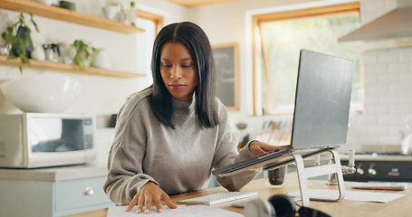 Image showing Laptop, documents and remote work with a woman entrepreneur in the kitchen of her home for small business. Computer, report and a young female freelance employee working on a startup from her house