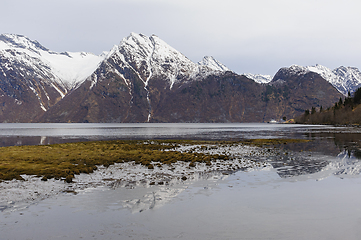 Image showing Overlooking the calm sea with snow-capped mountains in the backdrop at dusk.