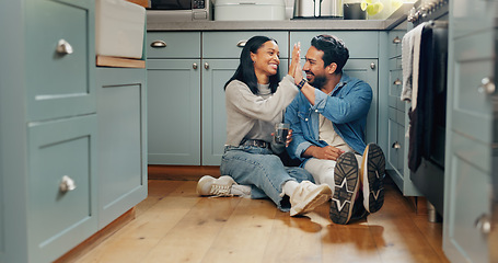 Image showing Couple, coffee and sitting on floor in kitchen for quality time or fun to celebrate or discussion. Love, smile and woman with high five are bonding together with caffeine and conversation or care.
