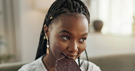 Image showing Home, eating and black woman on sofa, chocolate bar and dessert with happiness, relax and sugar snack in a lounge. African person, apartment or girl with candy, relaxing and dessert with comfort food