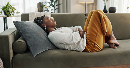 Image showing Home, pain and black woman on a couch, cramps and stomach with sickness, suffering and disease in the living room. African person, apartment and girl with abdominal problem, tummy ache and period