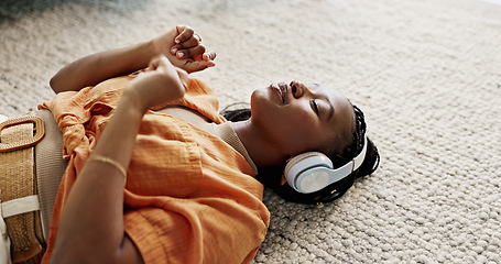 Image showing Headphones, relax and young woman on the floor in the living room listening to music or radio at modern apartment. Dancing, smile and young African female person streaming song in the lounge at home.