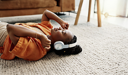 Image showing Headphones, relax and young woman on the floor in the living room listening to music or radio at modern apartment. Dancing, smile and young African female person streaming song in the lounge at home.