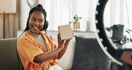 Image showing Wave, live streaming and happy black woman with box or product in home living room. Hello, influencer and person with package, record video on social media and content creation, ring light and phone