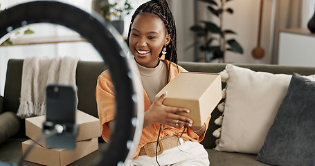 Image showing Influencer, live streaming and happy black woman with box or product in home living room. Hello, influencer and person with package, record video on social media and content creation, ring light and