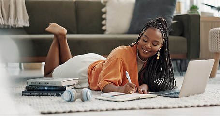 Image showing Laptop, happy and woman writing notes on the floor in the living room of modern apartment. Technology, smile and young African female university student studying on a computer in the lounge at home.