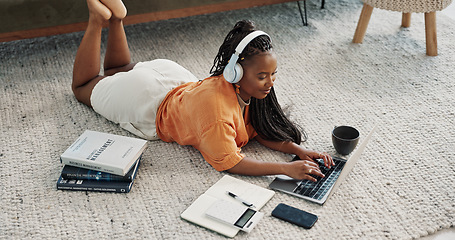 Image showing Laptop, headphones and young woman on the floor in living room of modern apartment. Tech, smile and young African female university student study and listen to music on computer in lounge at home.