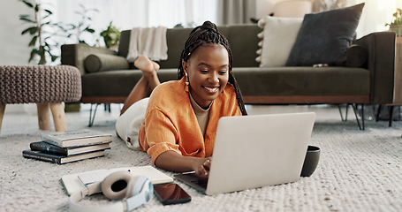 Image showing Laptop, smile and woman typing on the floor in the living room of modern apartment for research. Technology, happy and young African female university student studying on a computer in lounge at home