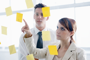 Image showing Teamwork, brainstorming and meeting in office with sticky notes for planning, ideas and schedule. Colleagues, thinking and pointing at paper for collaboration, vision and strategy on glass wall