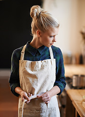 Image showing Chef, woman and tie apron in restaurant, kitchen or catering service at hotel for gastronomy. Uniform, cooking and person fasten clothes, culinary and preparation of professional waitress at job