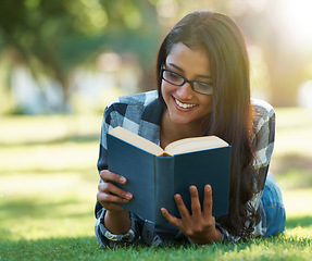 Image showing Happy woman, student and reading book on green grass for literature, studying or story in nature. Female person, smart or young adult with smile or glasses for chapter, learning or education at park