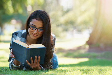 Image showing Happy woman, student and reading at park with book for literature, studying or story in nature. Female person, smart or young adult with smile or glasses for chapter, learning or outdoor education