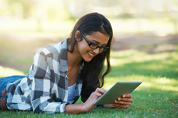 Image showing College, woman and typing on tablet in park with research, project or learning outdoor on campus. University, student and girl reading online with ebook, education and studying on grass in garden