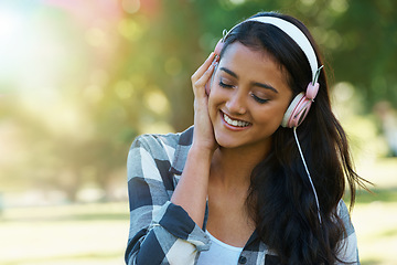 Image showing Music, headphones or happy woman in park to relax in garden, nature or field with smile or peace. Eyes closed, streaming or calm female person on break with playlist for radio, podcast or wellness