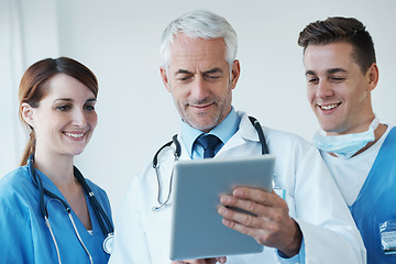 Image showing Tablet, discussion and doctor with nurses in hospital for medical diagnosis or treatment meeting. Team, digital technology and senior surgeon talk to healthcare workers for surgery research in clinic