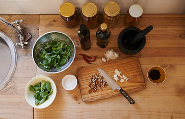 Image showing Salad, knife and ingredients on kitchen counter or cooking as leafy greens or nutrition, health or wellness. Wooden board, garlic and walnuts or spices as organic with lettuce, vegetables or top view