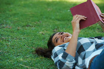 Image showing Happy woman, student and lying with book on green grass for literature, studying or story in nature. Female person, bookworm or young adult with smile and notebook for reading or education at park