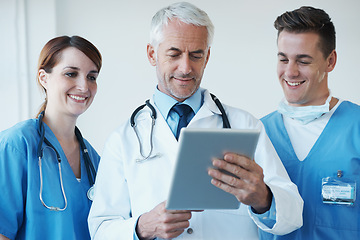 Image showing Tablet, meeting and doctor with nurses in hospital for medical diagnosis or treatment discussion. Team, digital technology and senior surgeon talk to healthcare workers for surgery research in clinic