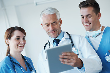 Image showing Tablet, team and doctor with nurses in hospital for medical diagnosis or treatment discussion. Meeting, digital technology and senior surgeon talk to healthcare workers for surgery research in clinic