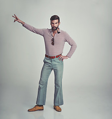 Image showing 70s, fashion and portrait of man with retro or vintage aesthetic in gray background of studio. Smoking, pipe and person dance with peace and confidence in funky sunglasses and unique style from past