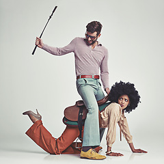 Image showing Retro, man and woman or riding crop in studio with piggyback, portrait and funny face for vintage style. Friends, people and 70s outfit with hipster clothes or comic expression with white background