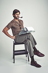 Image showing Fashion, man and typewriter or pipe in studio with vintage model, hipster outfit and confidence on chair. Relax, person and reading with 70s style, calm expression and smoking with white background
