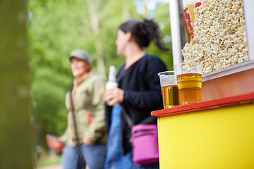 Image showing Beer, popcorn and vendor at festival closeup outdoor with people on blurred background for event or party. Summer, food or snack with alcohol in plastic cup on counter for drinking and celebration