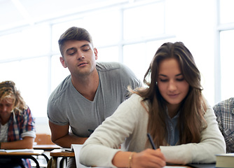 Image showing Students, write and cheat in classroom for learning, knowledge and development with notes at university. Man, education and college with peeping at test, exam or assessment of girl in lecture