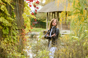 Image showing A young beautiful girl walks in the forest near a pond