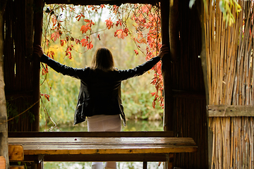 Image showing Young beautiful girl standing in the doorway of an old hut, rear view