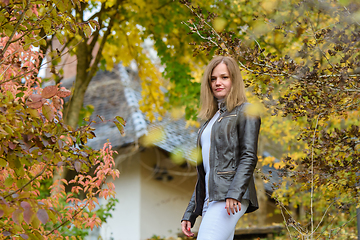 Image showing Young beautiful girl in casual clothes against the background of beautiful foliage and a private house