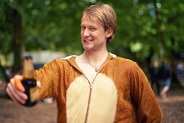 Image showing Halloween, costume and man with beer to drink, toast and happy celebration outdoor in bear outfit. Animal, suit and person smile in portrait with lager, bottle and drunk from drinking alcohol in park