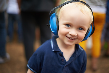 Image showing Portrait, child and noise cancelling headphones at outdoor event with smile, fun and music. Protection, happiness and boy toddler at festival, concert or live performance with soundproof headset.