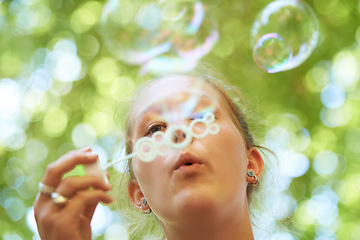 Image showing Woman, bubbles and blowing outdoor for fun on weekend, break or holiday for relax and summer entertainment. Person, closeup and plastic wand or toy for playing and leisure on vacation or adventure